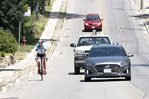 Passing a cyclist A cyclist rides near the curb while cars pass